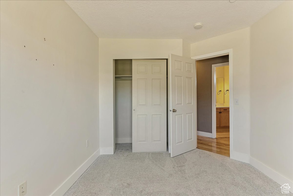 Unfurnished bedroom featuring light colored carpet, baseboards, and a closet