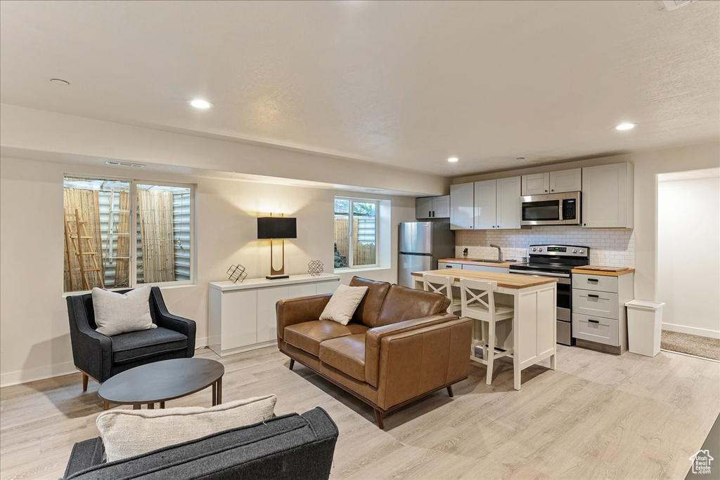 Living area featuring light wood-type flooring, baseboards, and recessed lighting