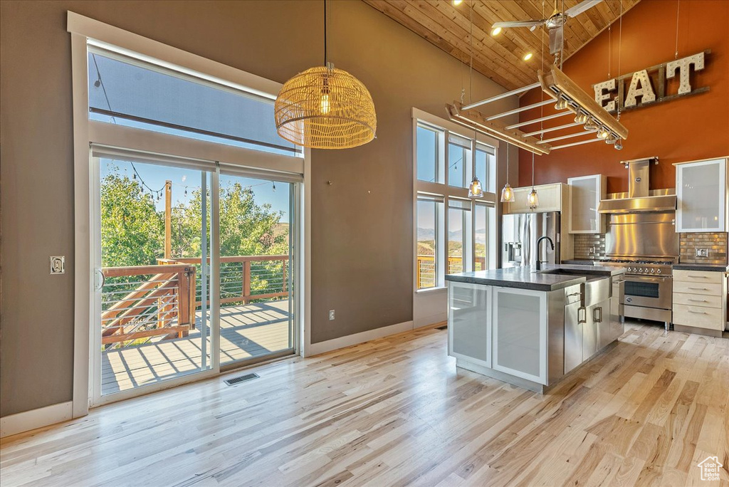 Kitchen featuring stainless steel appliances, wall chimney exhaust hood, high vaulted ceiling, wood ceiling, and dark countertops