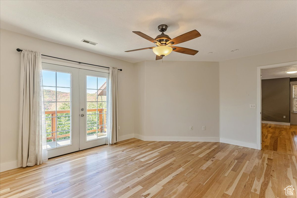 Unfurnished room with french doors, light wood-type flooring, a ceiling fan, and baseboards
