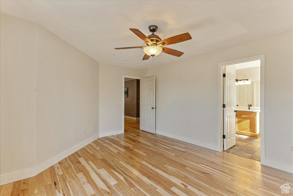 Unfurnished bedroom with light wood finished floors, baseboards, ensuite bath, and a ceiling fan