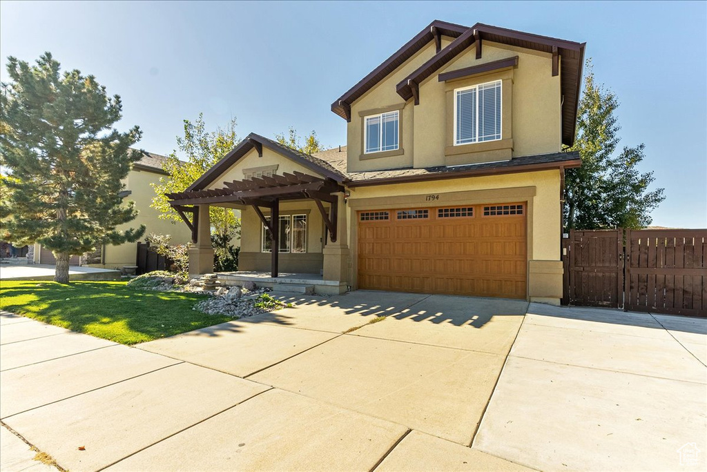 Craftsman inspired home featuring stucco siding, concrete driveway, an attached garage, a pergola, and a gate