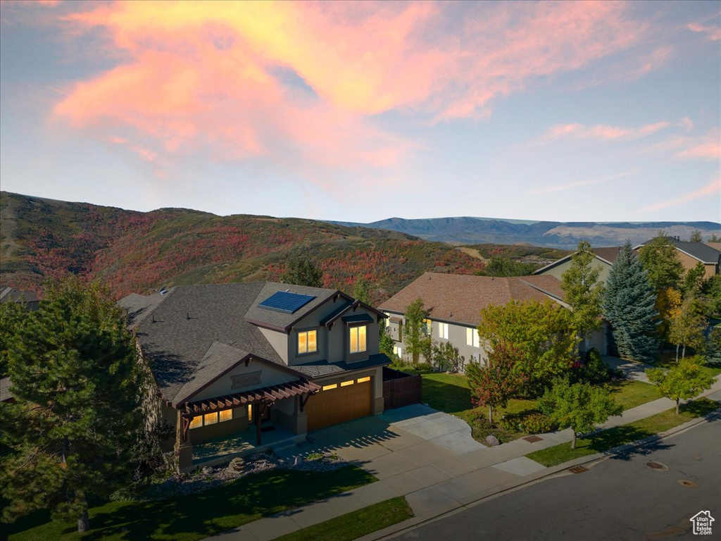View of front facade with driveway, a garage, roof mounted solar panels, and a mountain view
