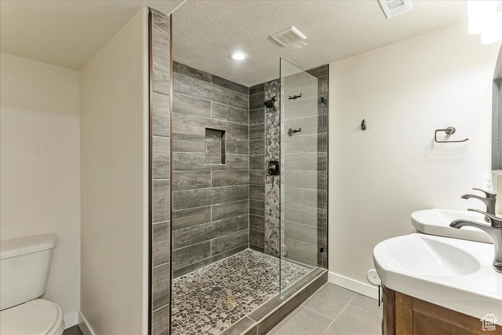 Bathroom featuring tile patterned flooring, vanity, a shower stall, toilet, and baseboards