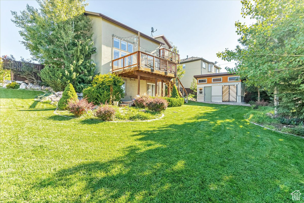 Back of house featuring a wooden deck, stucco siding, and a lawn