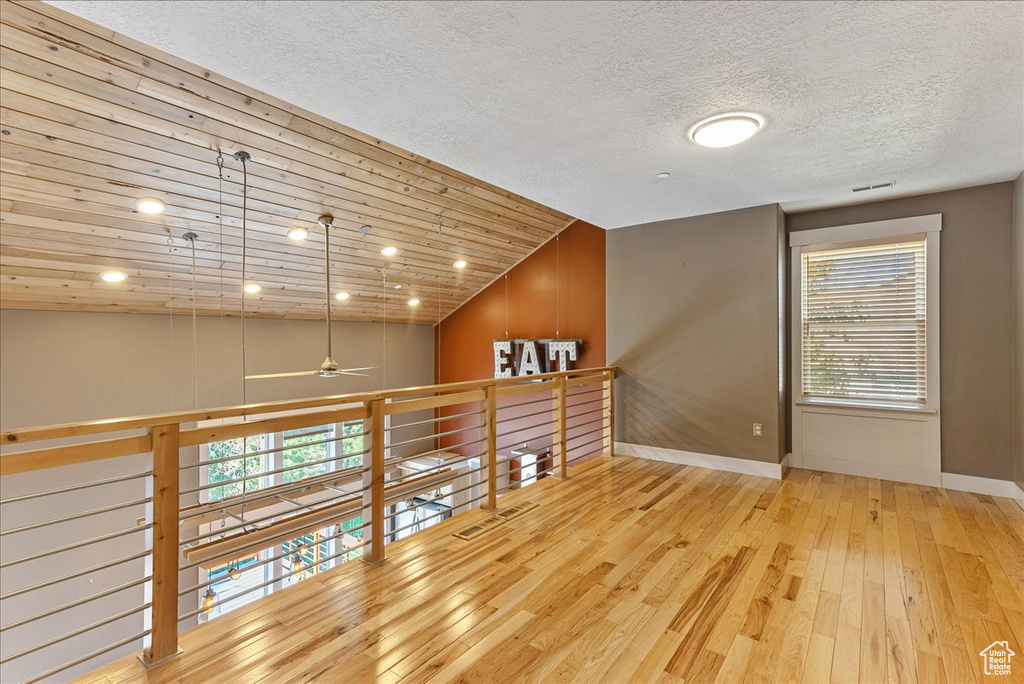 Spare room featuring baseboards, ceiling fan, hardwood / wood-style flooring, a textured ceiling, and vaulted ceiling