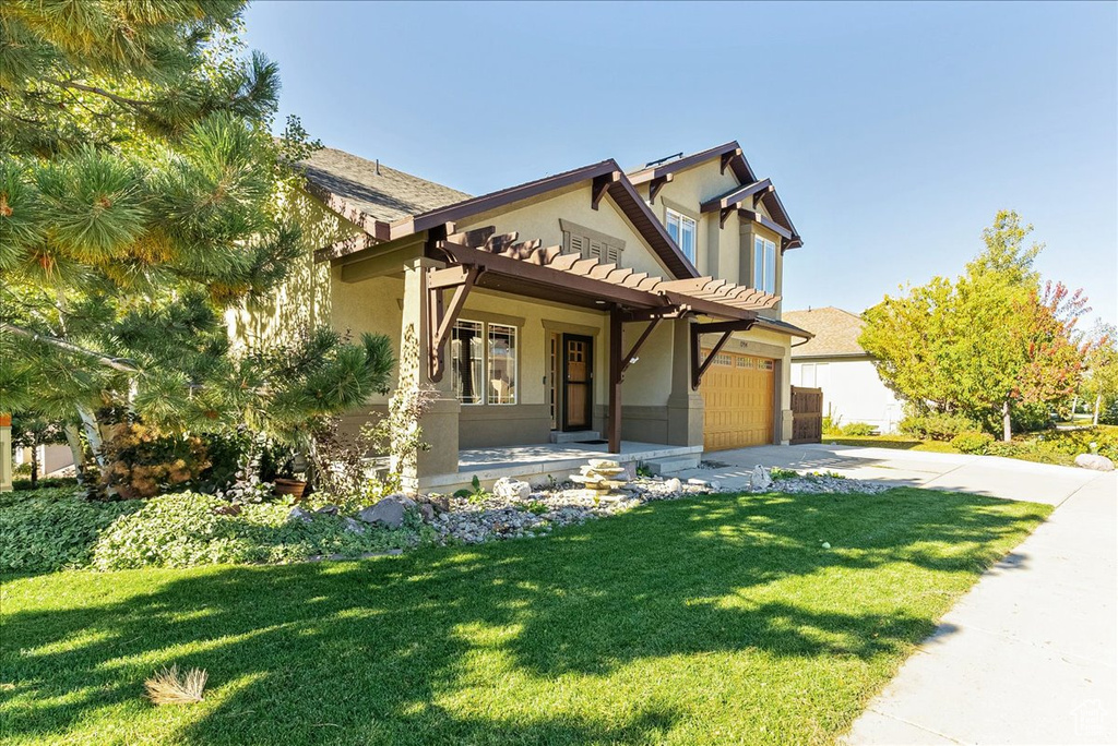 View of front of home featuring stucco siding, driveway, a front lawn, a porch, and a garage