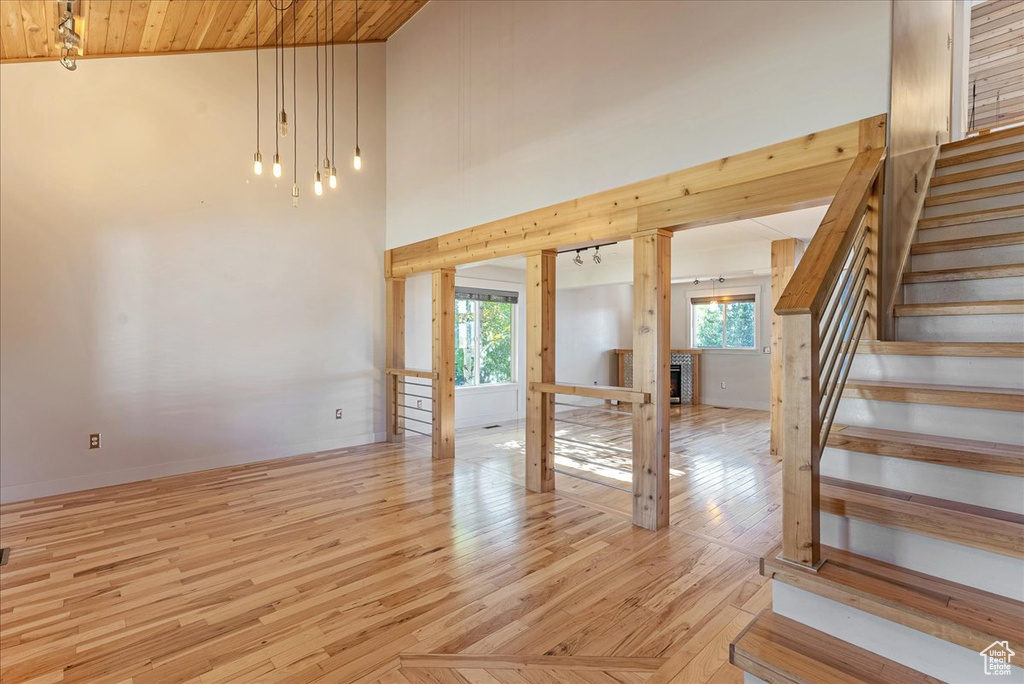 Unfurnished living room featuring stairway, light wood-style floors, and wooden ceiling