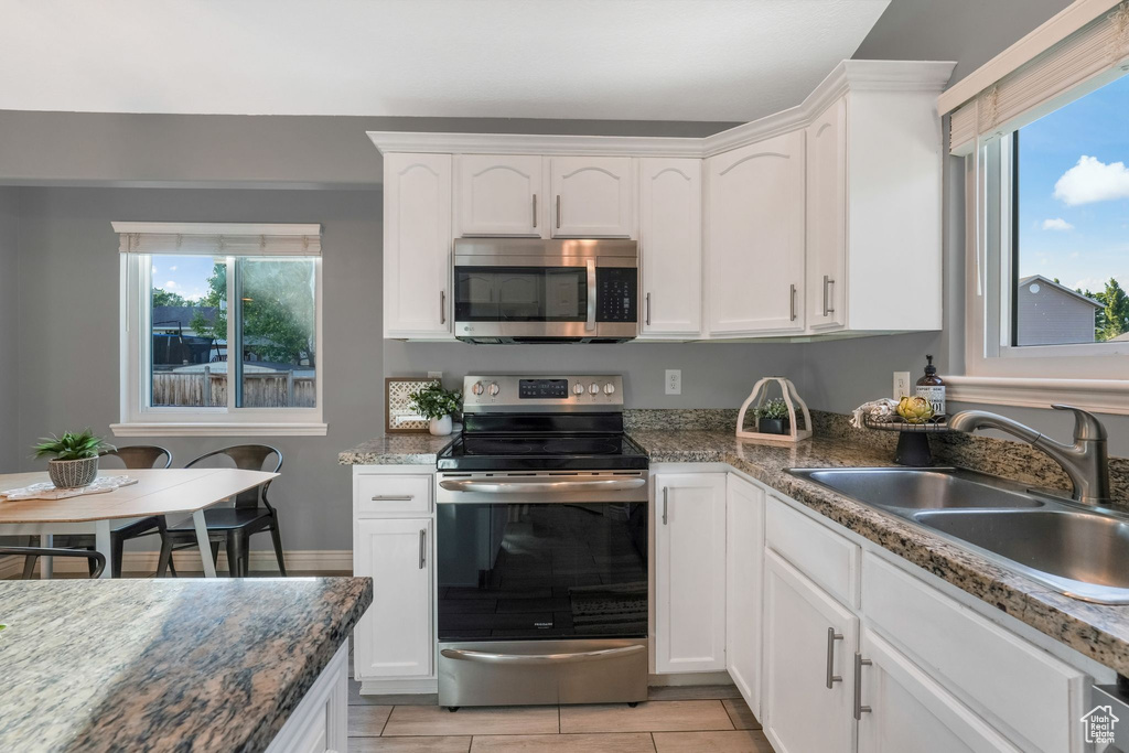 Kitchen with appliances with stainless steel finishes, plenty of natural light, and white cabinets