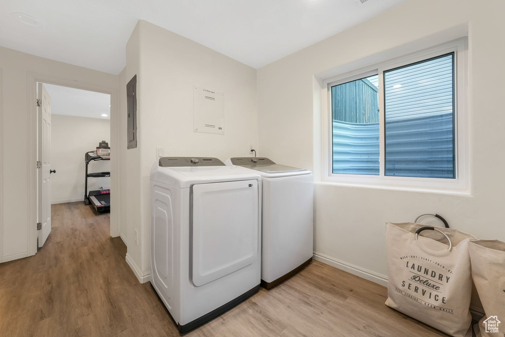 Laundry area featuring washer and clothes dryer, light wood finished floors, and electric panel