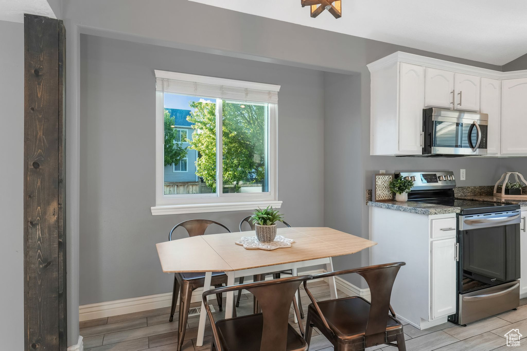Kitchen with stainless steel appliances, white cabinetry, and wood tiled floors