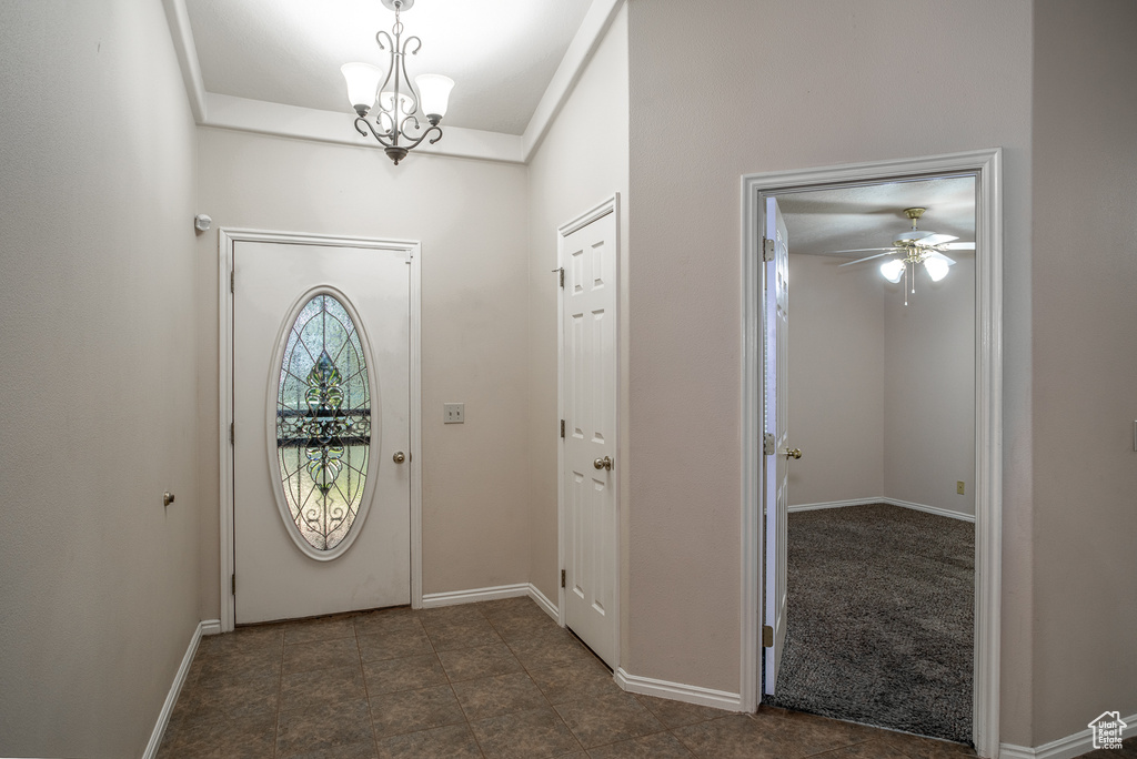 Entrance foyer featuring a ceiling fan, a chandelier, and baseboards