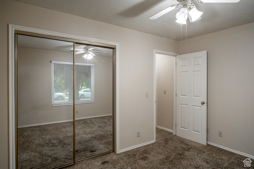 Unfurnished bedroom featuring carpet floors, a closet, ceiling fan, baseboards, and a textured ceiling