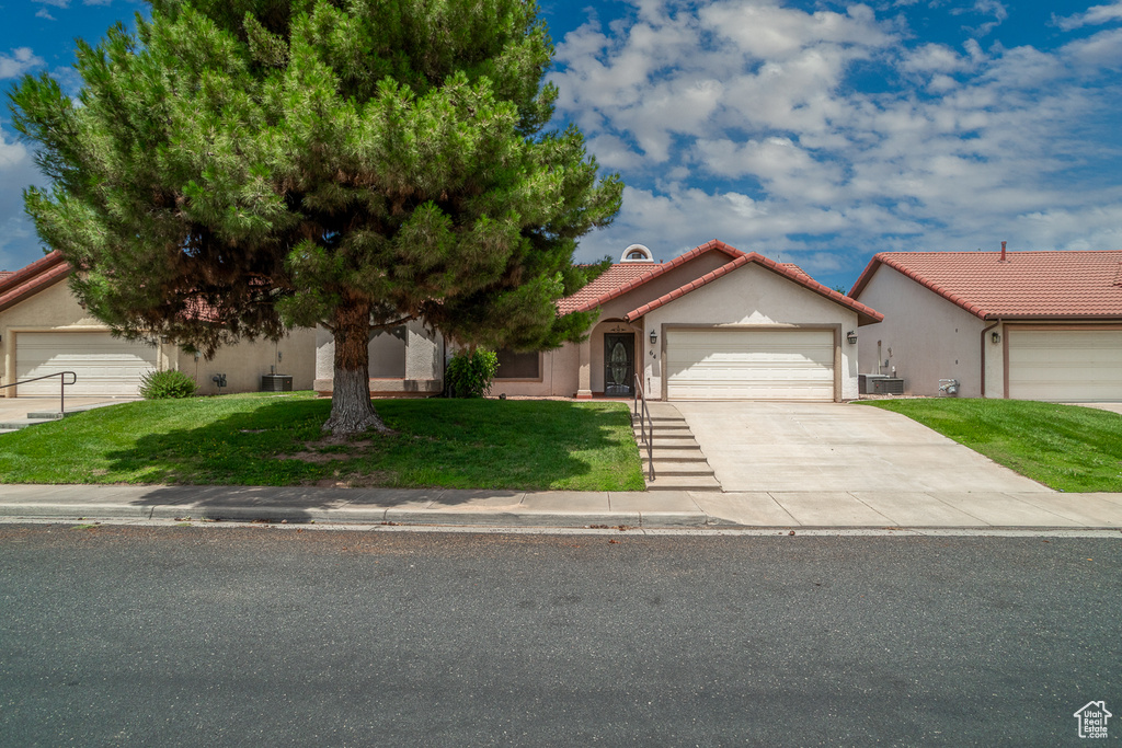 Mediterranean / spanish home featuring a garage, a front lawn, driveway, a tile roof, and stucco siding