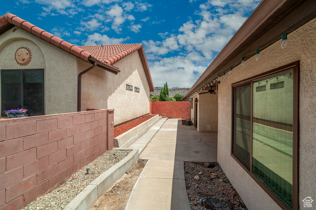 View of side of property with stucco siding, a tiled roof, and a patio area
