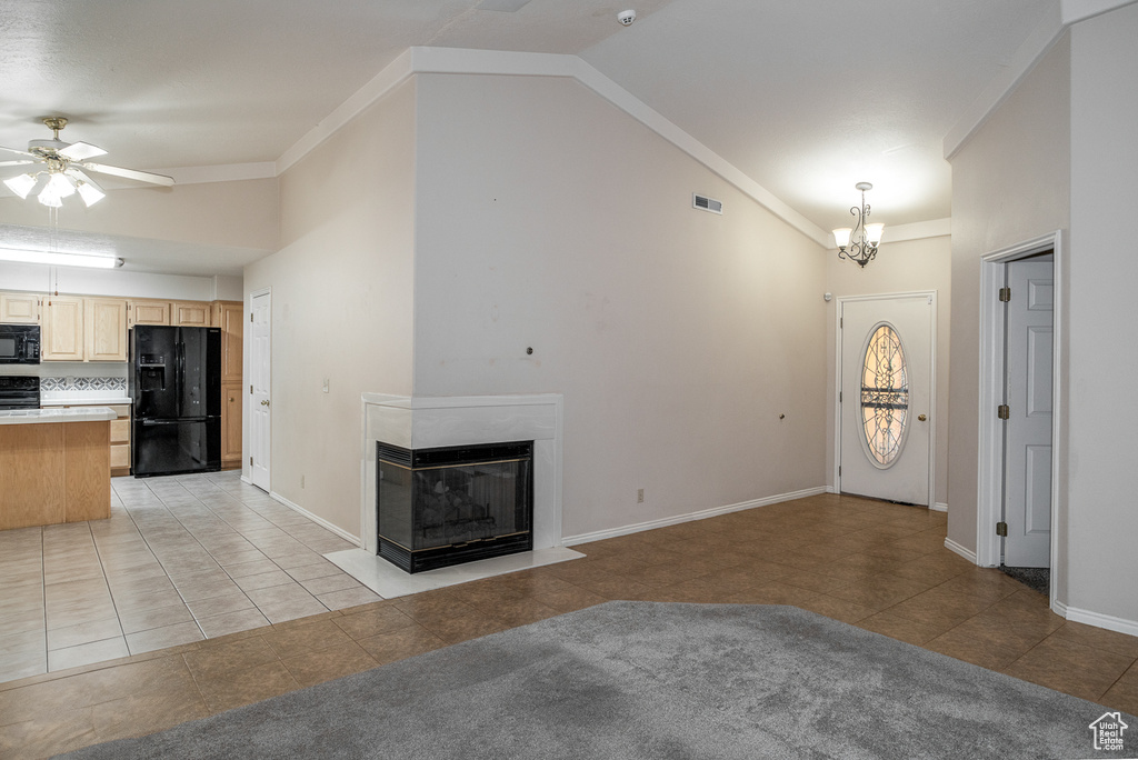 Unfurnished living room with vaulted ceiling, ceiling fan, light tile patterned flooring, a chandelier, and a multi sided fireplace