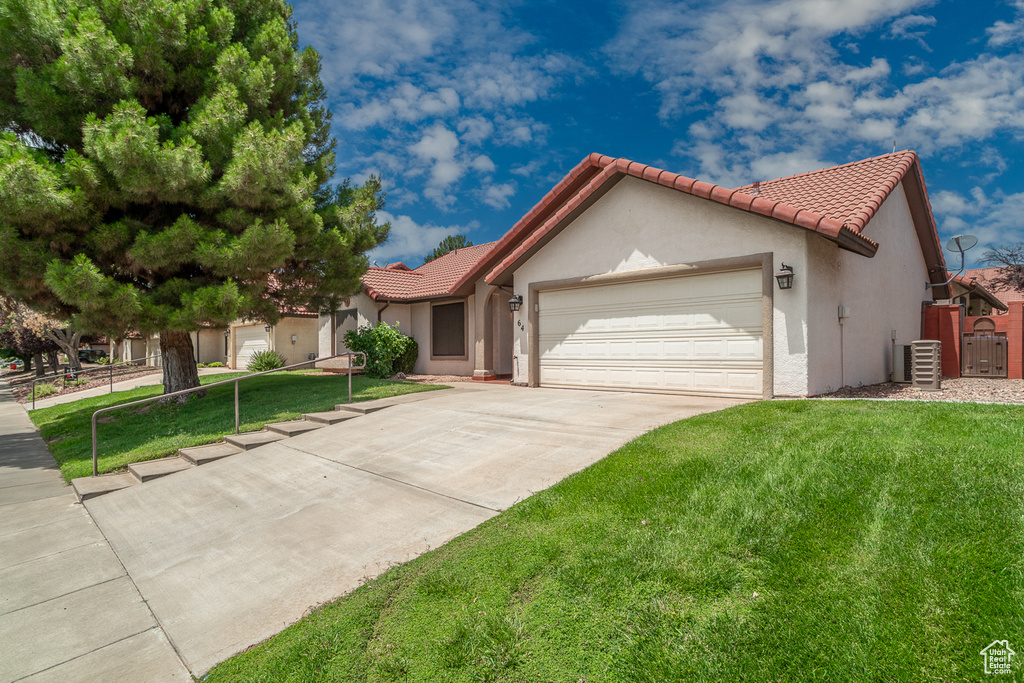 View of front of house featuring a garage, a front yard, a tiled roof, and concrete driveway