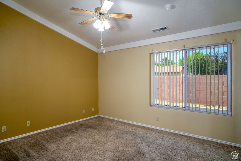 Carpeted empty room featuring ceiling fan, baseboards, and a smoke detector