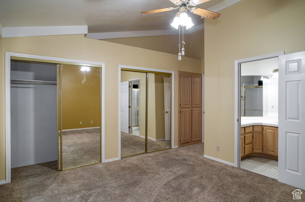 Unfurnished bedroom with two closets, vaulted ceiling, carpet floors, and ensuite bathroom