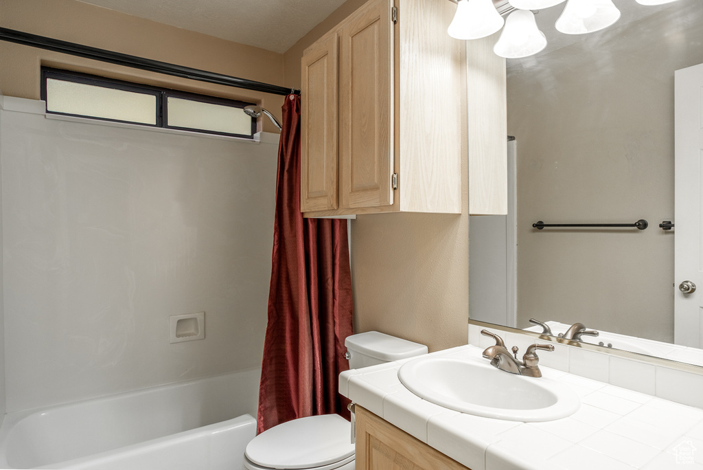 Bathroom featuring vanity, toilet, shower / bathtub combination with curtain, and a chandelier