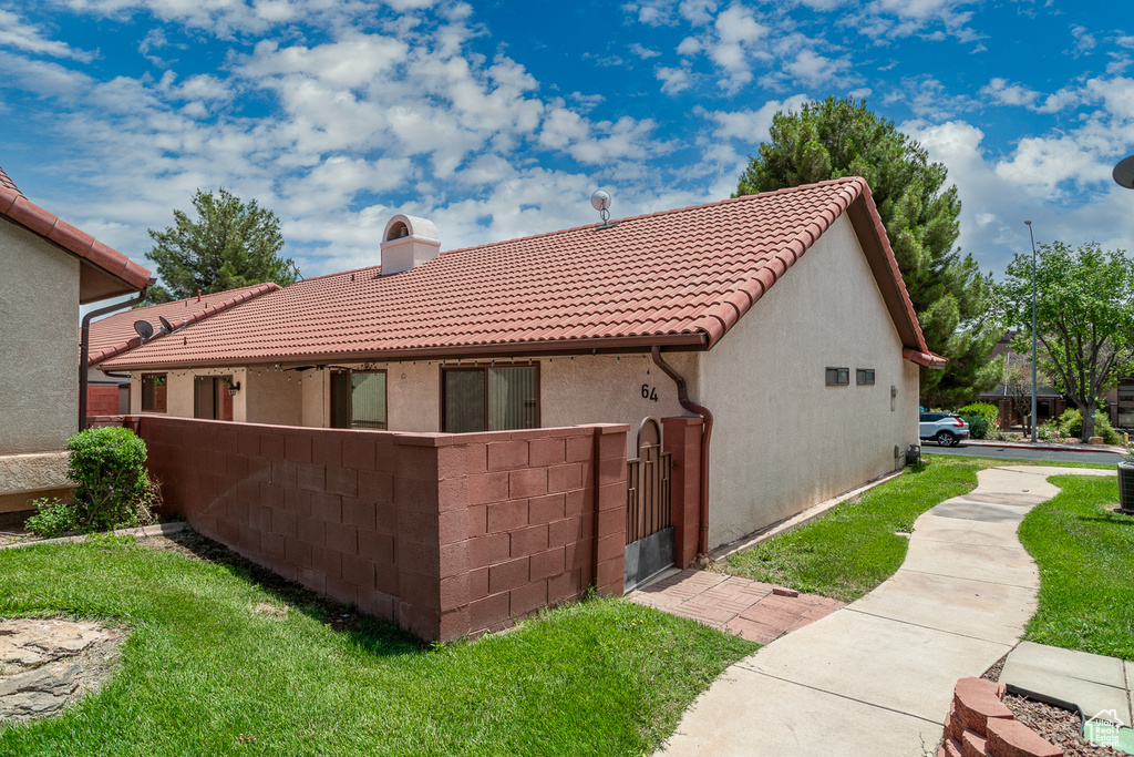 Rear view of property featuring a tiled roof, a chimney, stucco siding, and a gate