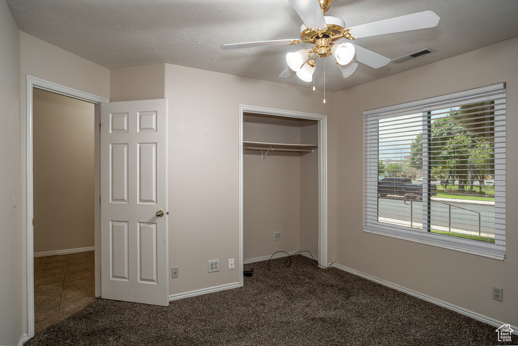 Unfurnished bedroom featuring carpet flooring, a closet, baseboards, and ceiling fan