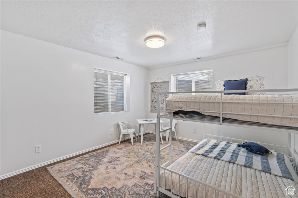Bedroom featuring baseboards, a textured ceiling, and carpet flooring