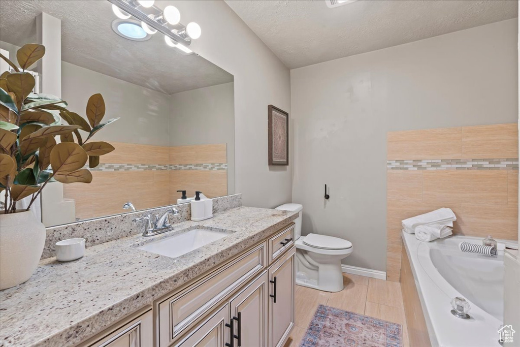 Full bath featuring vanity, a garden tub, toilet, and baseboards
