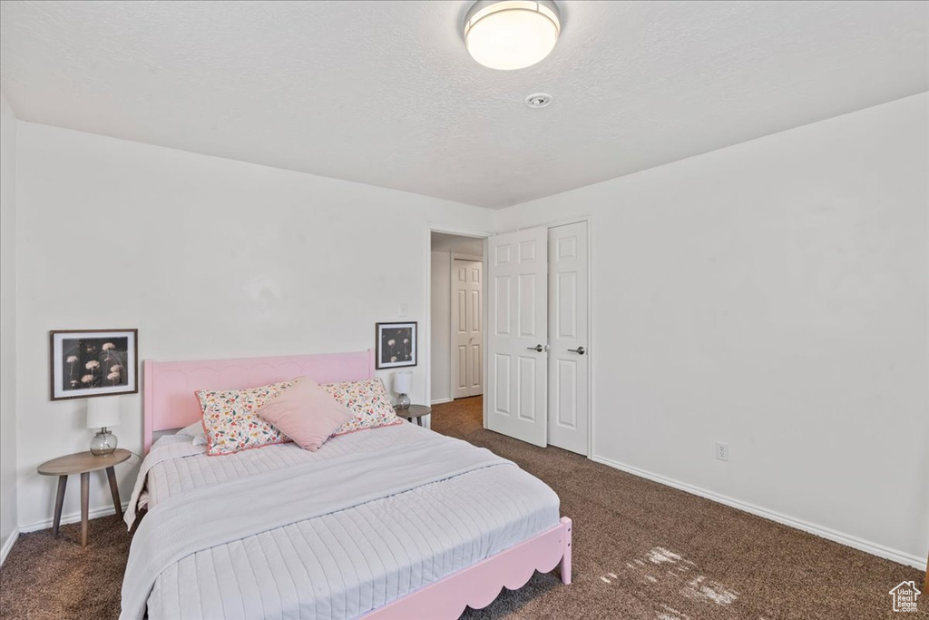 Bedroom with carpet floors, baseboards, and a textured ceiling