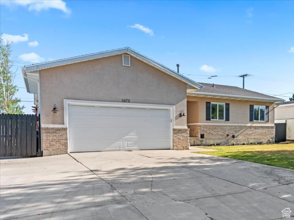 Ranch-style house with brick siding, stucco siding, a garage, and concrete driveway