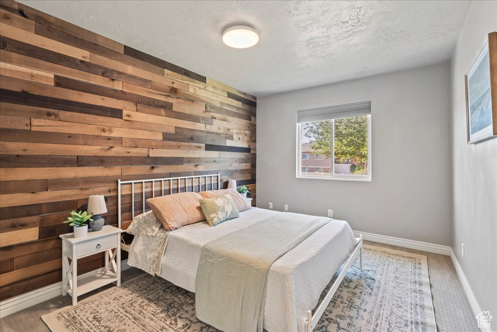 Bedroom with wooden walls, baseboards, and a textured ceiling