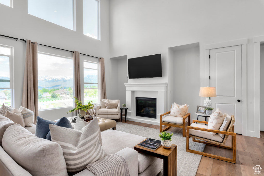 Living area with a high ceiling, a glass covered fireplace, and light wood finished floors