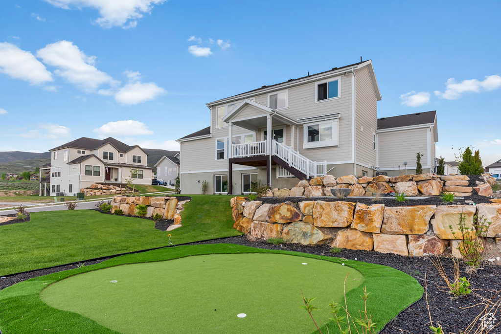 Back of house featuring a putting area, stairs, a yard, and a deck