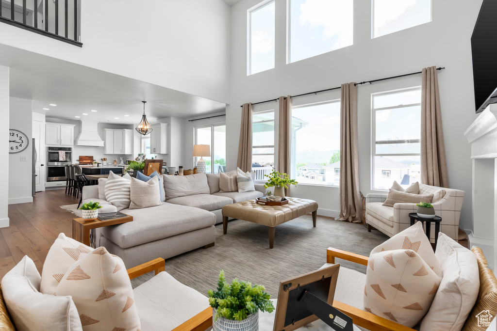 Living area featuring a towering ceiling, light wood-style floors, recessed lighting, and plenty of natural light