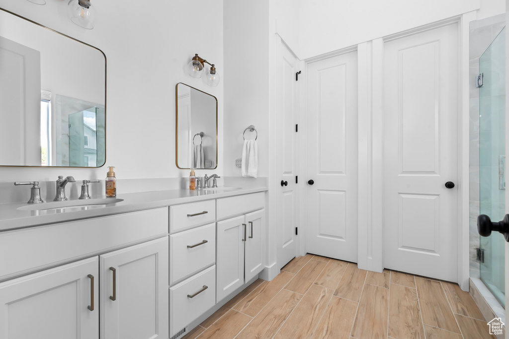 Full bath with double vanity, a stall shower, and wood tiled floors