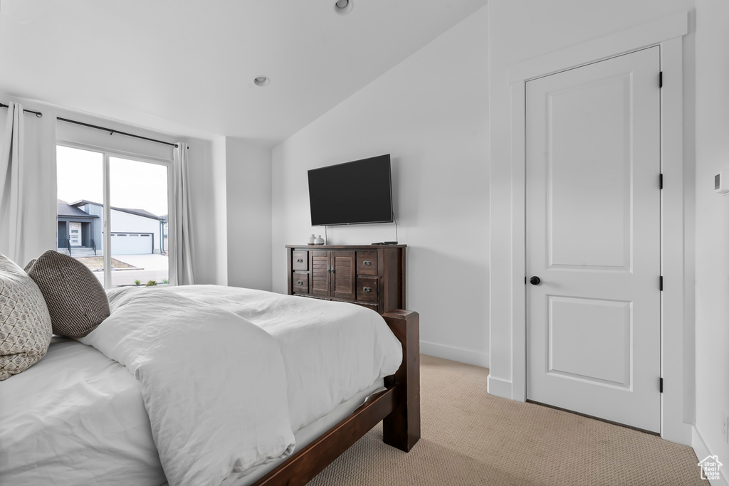 Bedroom featuring vaulted ceiling, carpet flooring, and access to outside