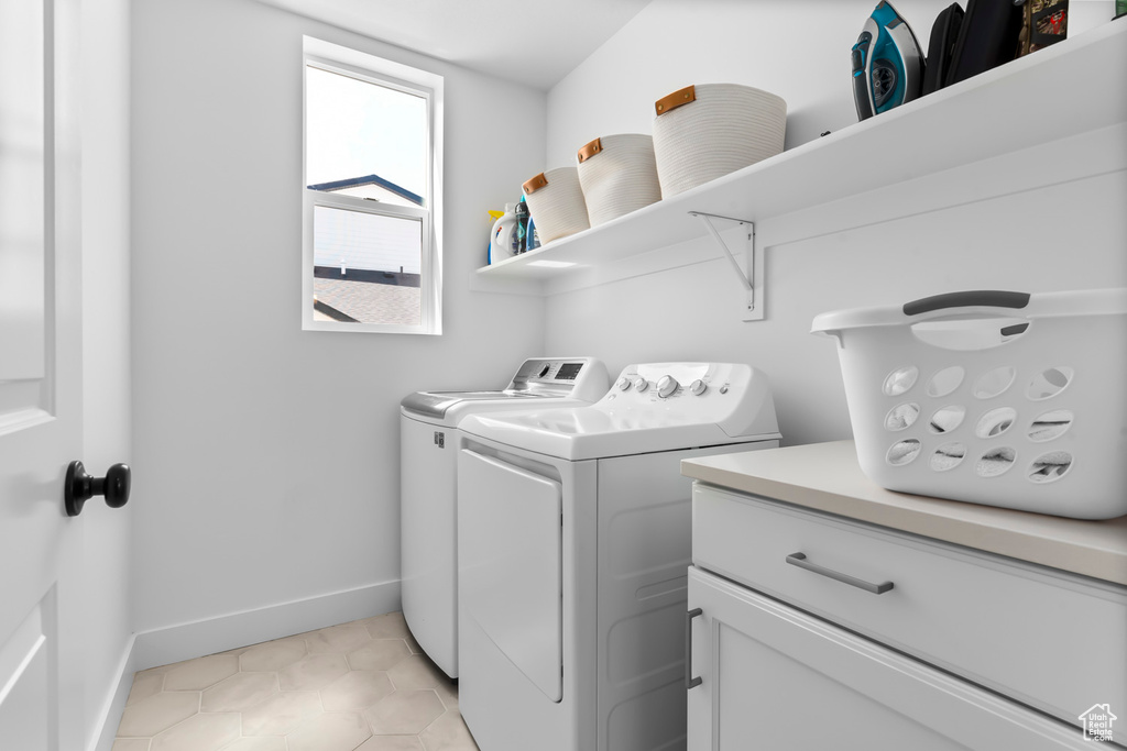 Laundry room with independent washer and dryer and light tile patterned floors