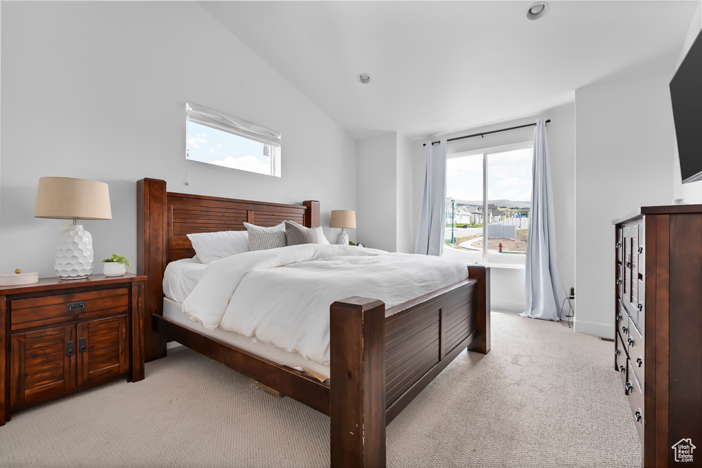 Bedroom with light colored carpet, multiple windows, vaulted ceiling, and recessed lighting