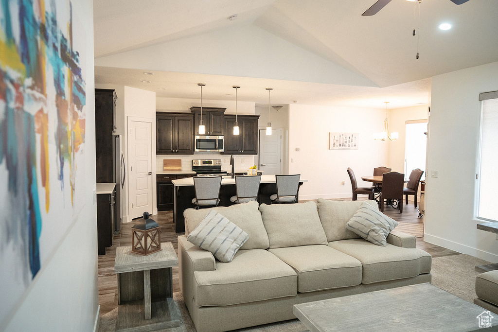 Living room featuring lofted ceiling, a ceiling fan, recessed lighting, and a chandelier