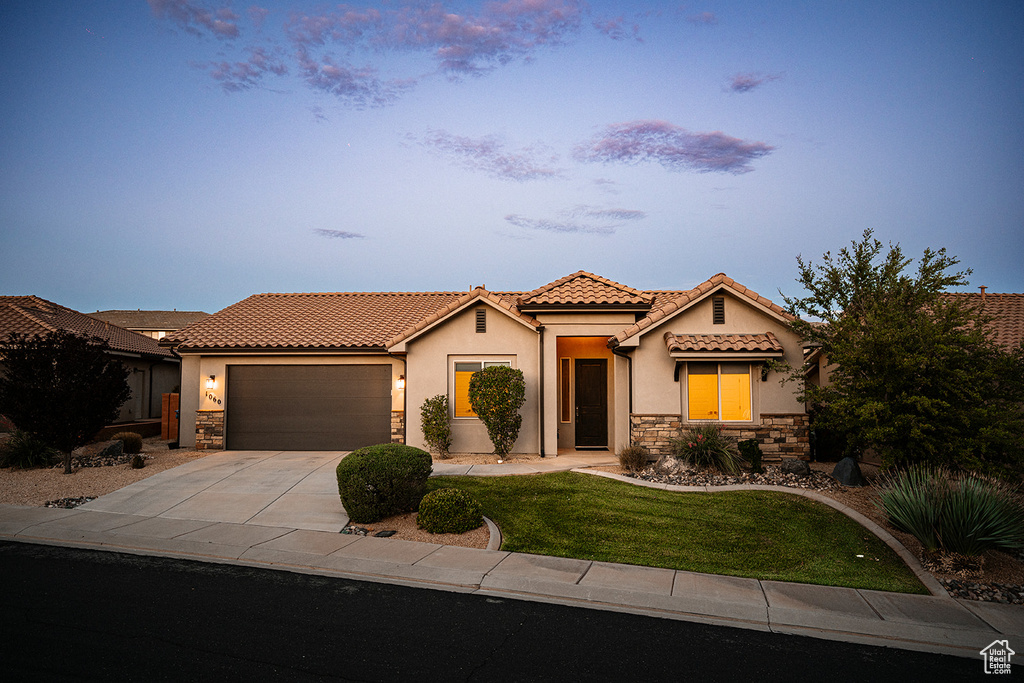 Mediterranean / spanish home featuring stone siding, a tiled roof, stucco siding, a garage, and driveway