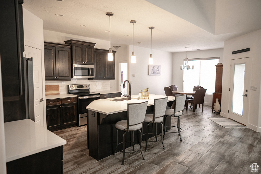Kitchen featuring appliances with stainless steel finishes, a kitchen breakfast bar, light countertops, decorative backsplash, and recessed lighting