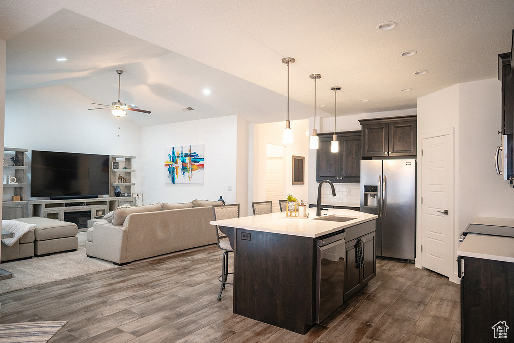 Kitchen with stainless steel appliances, dark brown cabinetry, dark wood-style floors, light countertops, and a ceiling fan