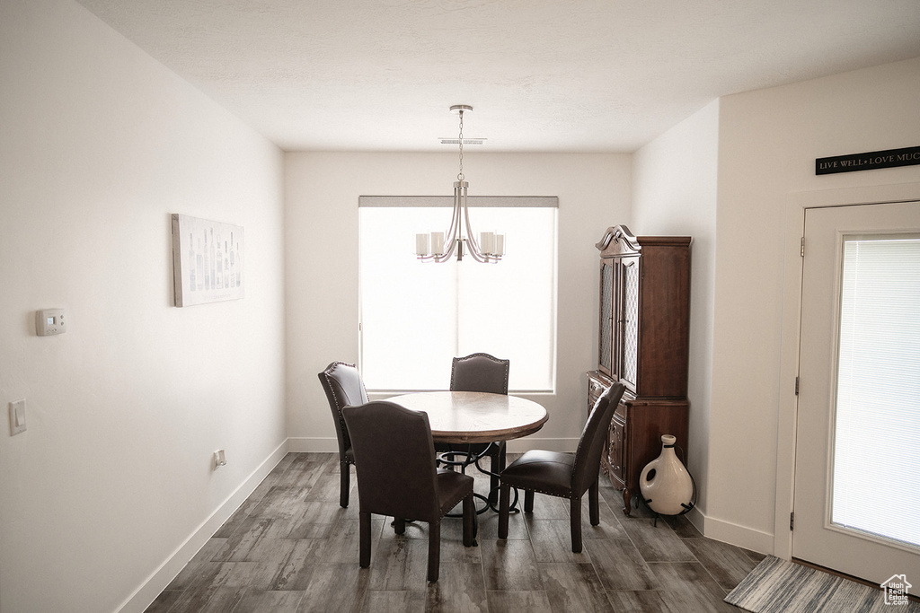 Dining space with a chandelier and dark wood-type flooring