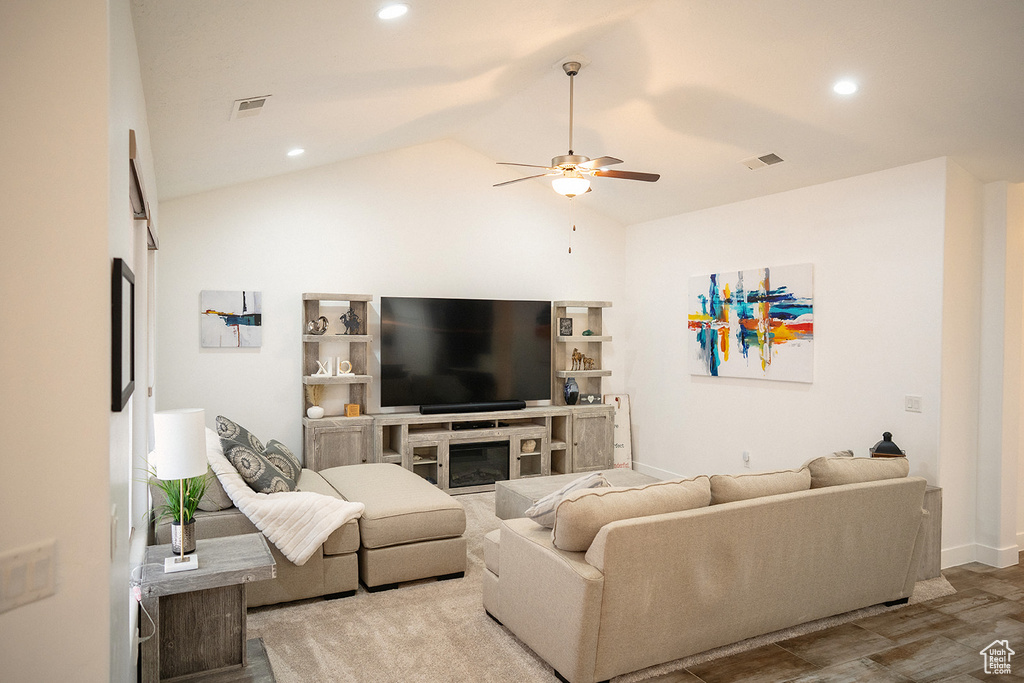 Living area with a ceiling fan, lofted ceiling, a glass covered fireplace, recessed lighting, and wood finished floors