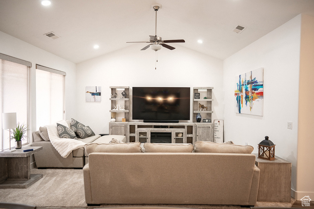 Living room with a ceiling fan, lofted ceiling, recessed lighting, and a glass covered fireplace