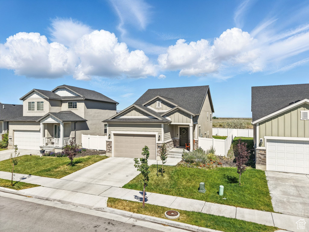 View of front of property featuring board and batten siding, stone siding, concrete driveway, and an attached garage
