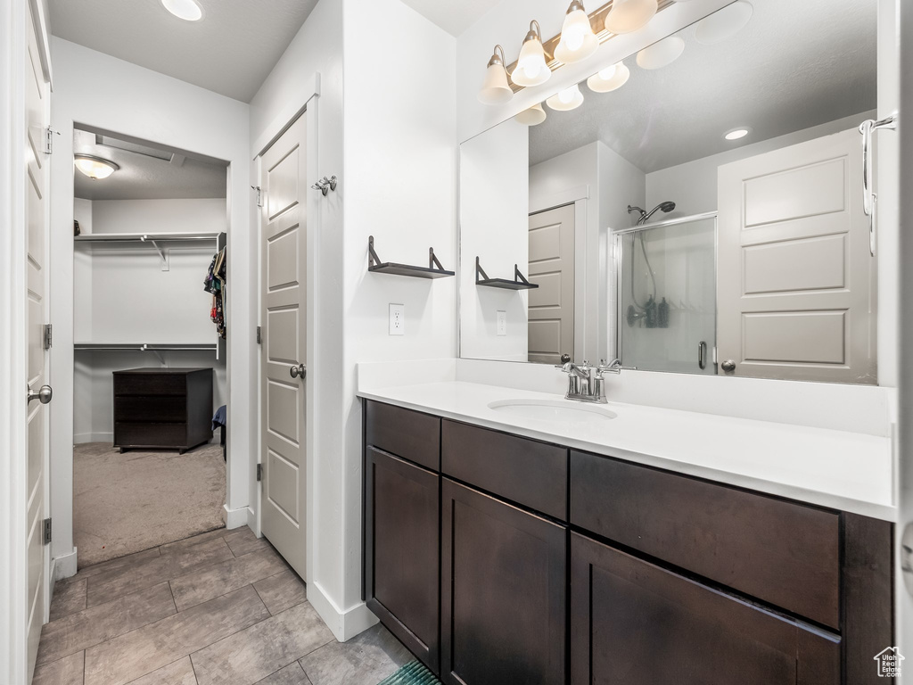 Bathroom featuring a shower stall, vanity, and a spacious closet