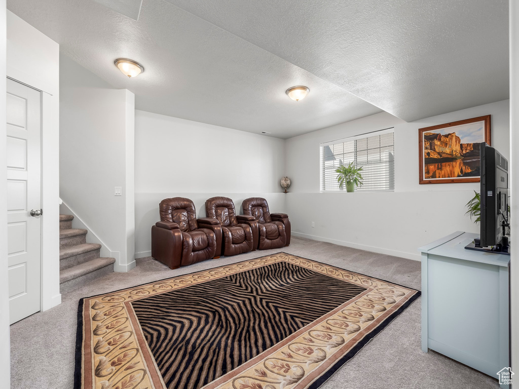 Living area featuring carpet flooring, a textured ceiling, and stairs