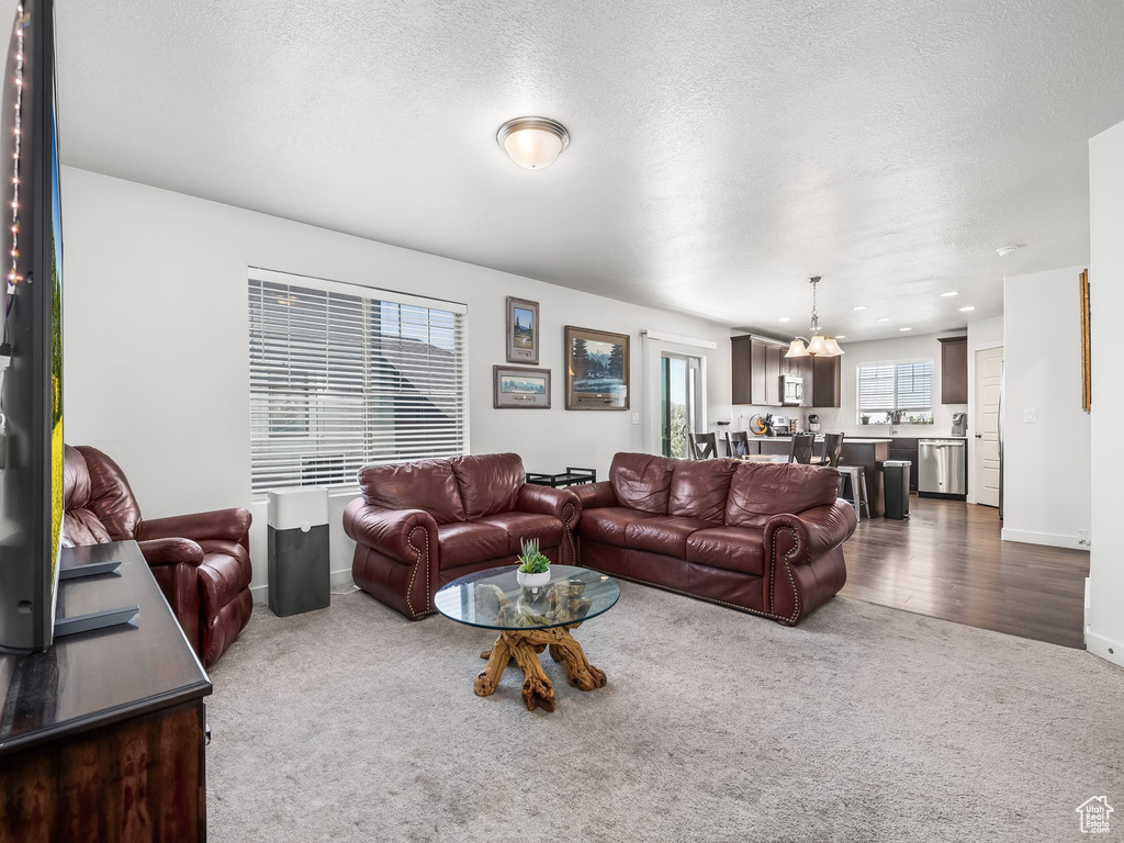 Living area featuring dark colored carpet, a chandelier, a textured ceiling, and dark wood finished floors