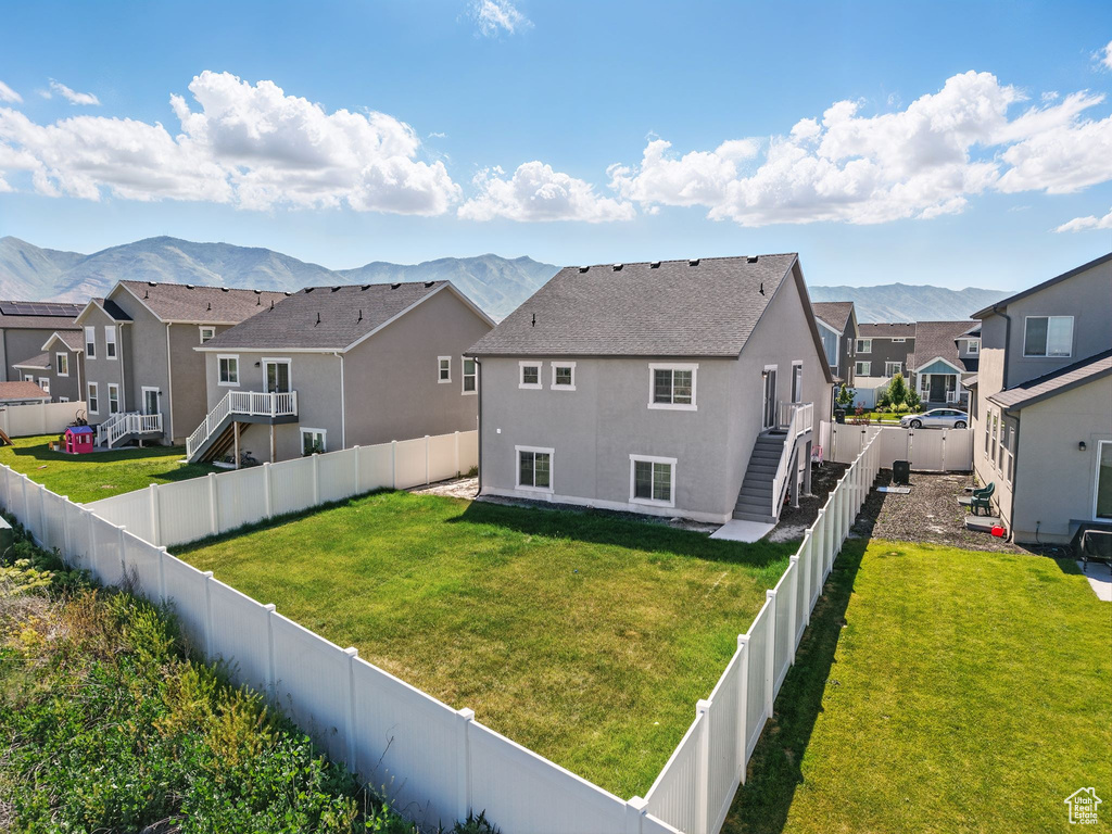 Back of house with a residential view, a mountain view, a fenced backyard, and stucco siding